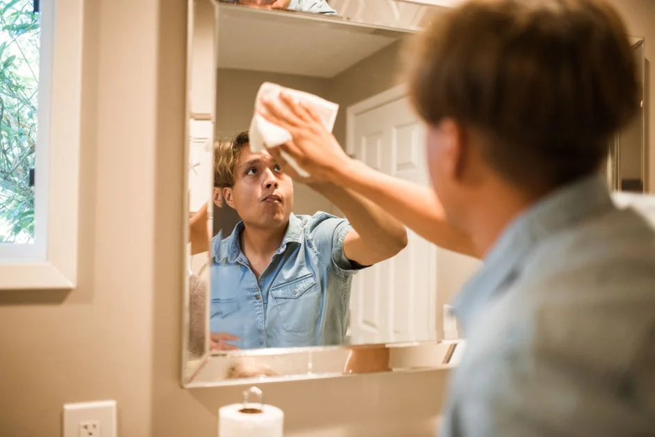 Vue latérale d’un jeune employé tenant une pile de serviettes blanches, debout dans la salle de bain d’un hôtel de luxe